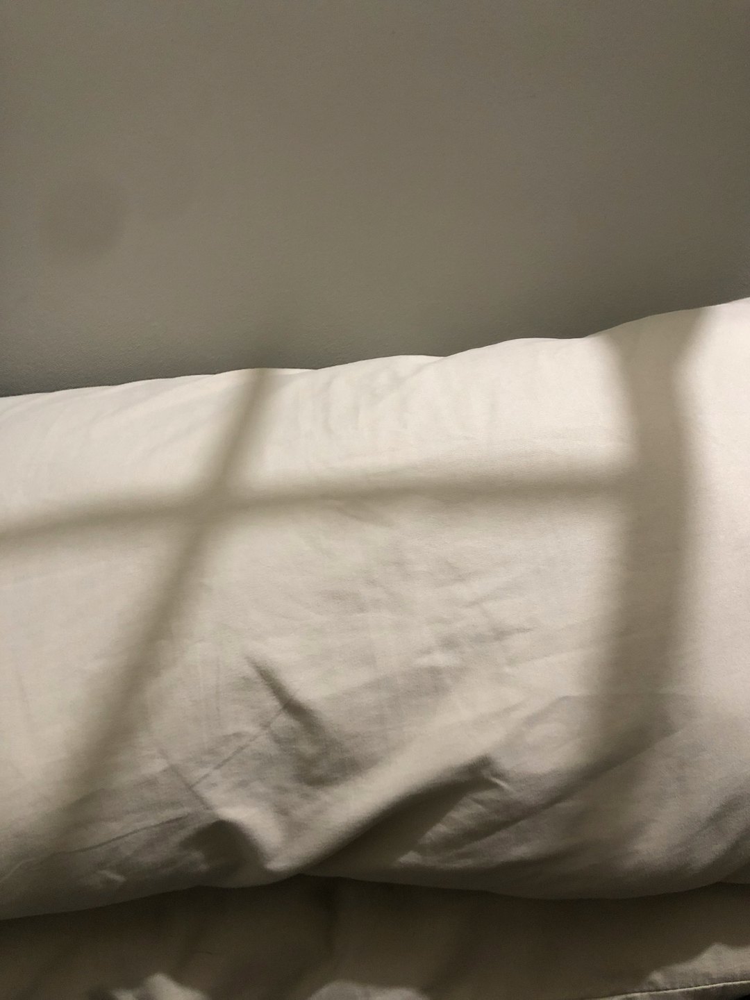 Geometryczne cienie padają na miękkie fałdy poduszki.